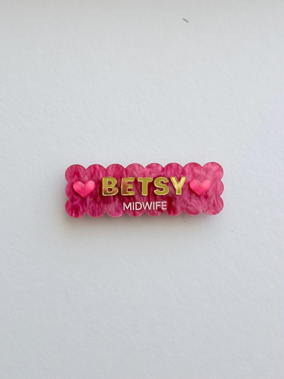 Pink scalloped Christmas name badge with hearts reading Betsy, Midwife