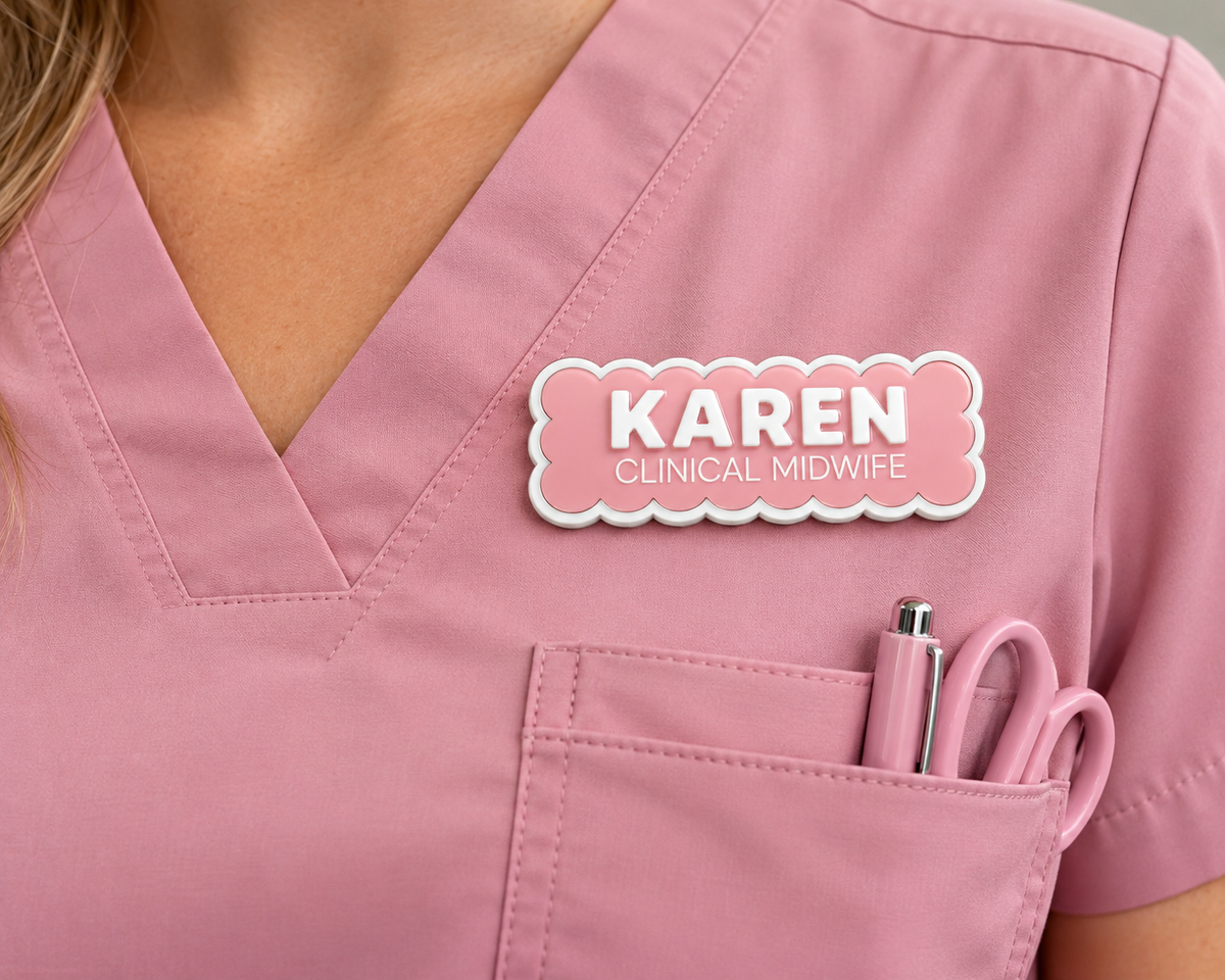Pink scalloped name badge reading 'Karen – Clinical Midwife' worn on a pink scrub top
